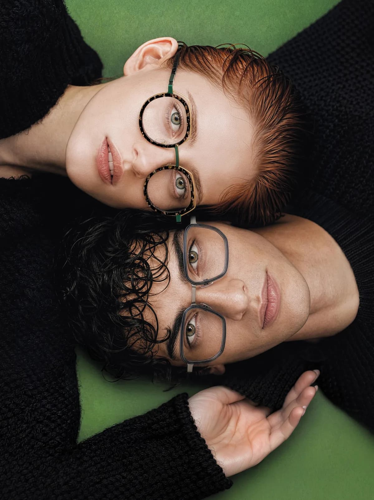 Two people lying side by side on a green surface, wearing differently shaped J.F. Rey optical frames