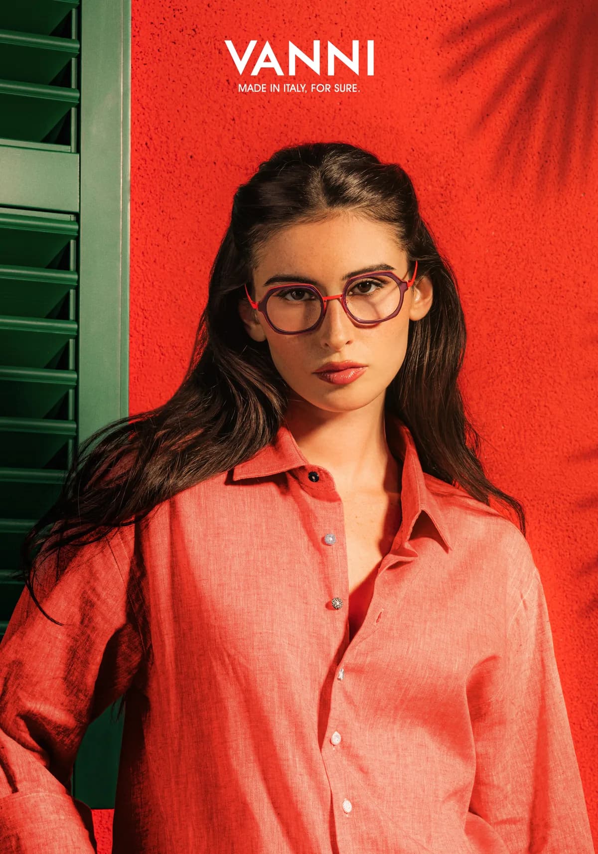 Woman wearing red and purple VANNI optical frames beside green shutters