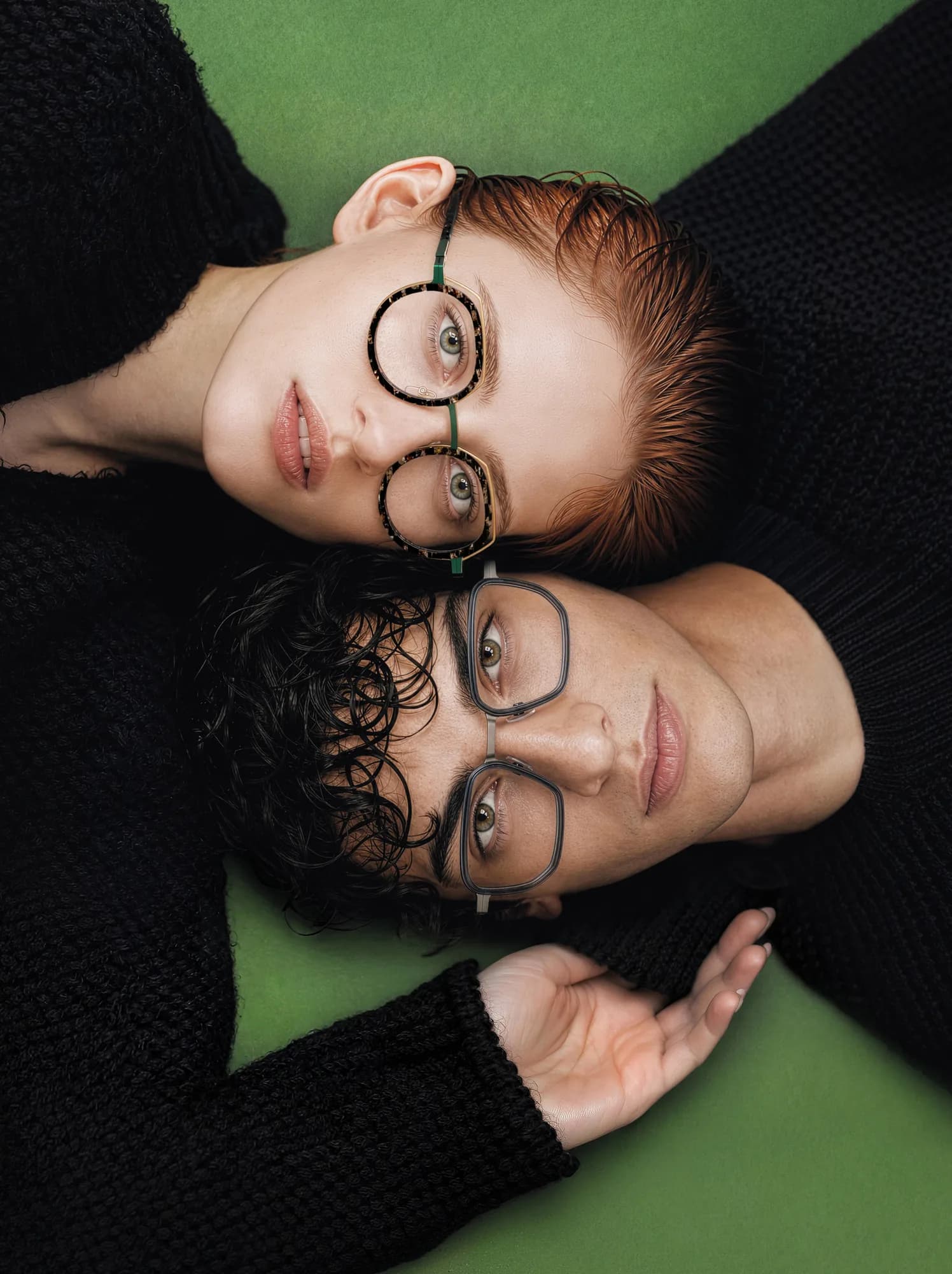 Portrait of two adults reclining in J.F. Rey optical frames against green