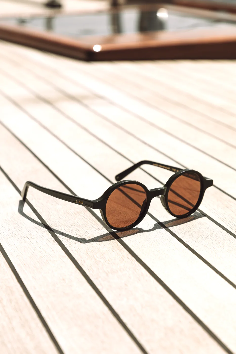 L.G.R GONE still-life image with round sunglasses on a boat deck
